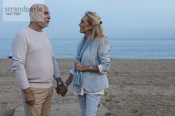 Spanien  Barcelona  glückliches älteres Ehepaar Hand in Hand am Strand in der Abenddämmerung