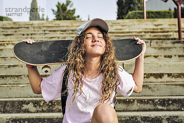 Mädchen mit Skateboard auf Stufen sitzend