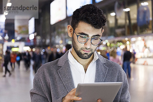 Deutschland  München  Porträt eines jungen Geschäftsmannes mit digitalem Tablet am Hauptbahnhof