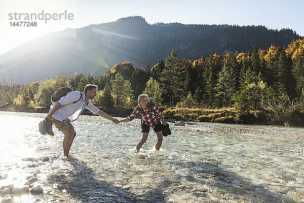 Österreich  Alpen  Ehepaar auf einer Wanderung watend in einem Bach