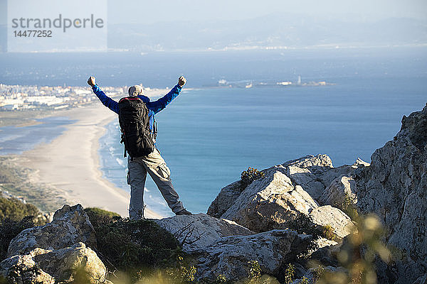 Spanien  Andalusien  Tarifa  Mann auf einer Wanderung an der Küste mit jubelnder Aussicht