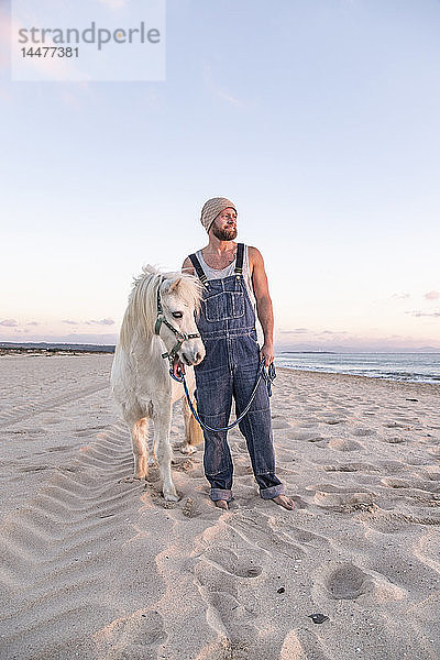 Spanien  Tarifa  Mann mit Pony am Strand stehend