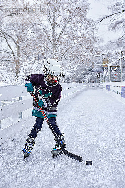 Junge spielt Eishockey auf der Eisbahn