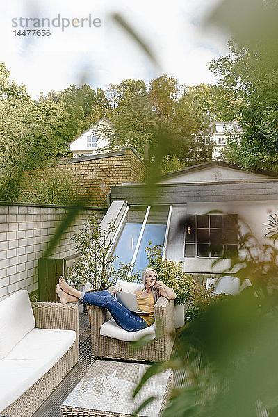 Frau mit Laptop entspannt sich auf der Terrasse