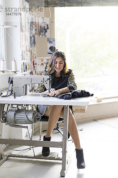 Junge Designerin mit Nähmaschine in einem Atelier