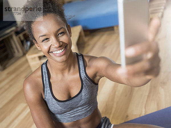 Lächelnde junge Frau in Sportkleidung nimmt ein Selfie