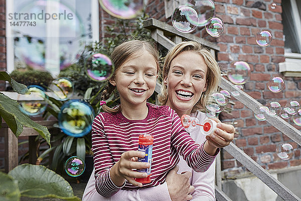 Glückliche Mutter und Tochter machen Seifenblasen