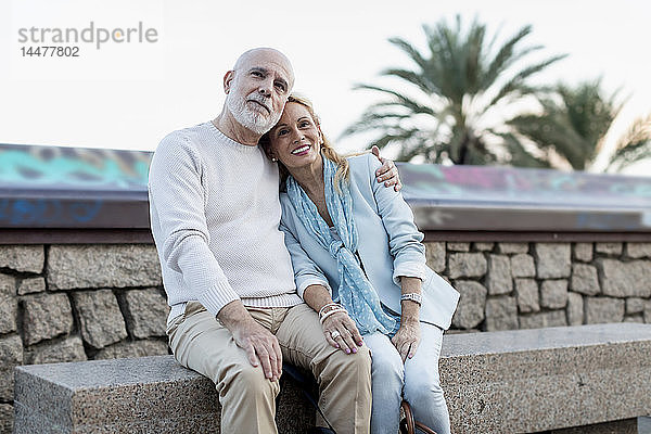 Spanien  Barcelona  glückliches älteres Paar umarmt sich auf einer Bank