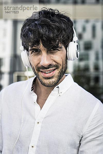 Porträt eines jungen Mannes mit Kopfhörern in der Stadt