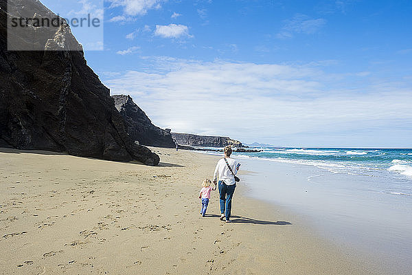 Spanien  Kanarische Inseln  Fuerteventura  La Pared  Playa del Viejo Rey  Mutter und Tochter am Strand spazieren
