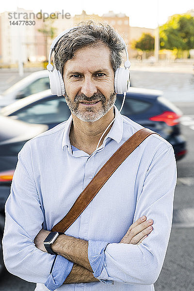 Porträt eines reifen Mannes mit Kopfhörern an einer Straße stehend