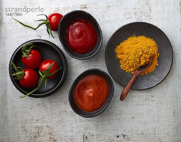 Tomaten  Currypulver  Chili-Ketchup und Tomatenketchup in Schalen