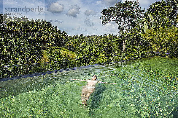 Indonesien  Bali  Ubud  Kamandalu Ubud Resort  Frau geniesst den wunderschönen überlaufenden Pool