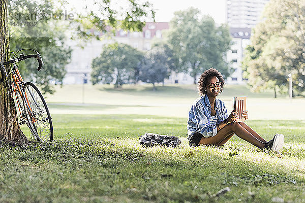 Lächelnde junge Frau ruht mit Tablette im Park