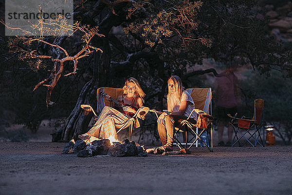 Namibia  Freunde sitzen am Lagerfeuer und spielen Gitarre