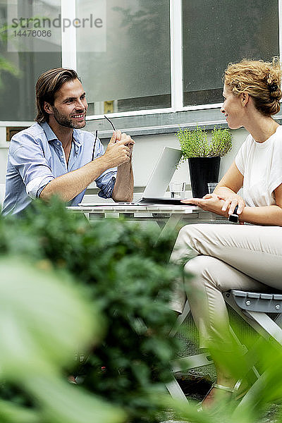 Glückliches Paar  das von zu Hause aus arbeitet und in seinem Garten sitzt