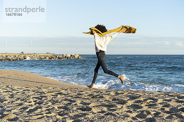 Am Strand laufende Frau mit gelbem Schal