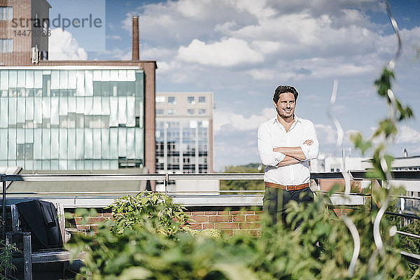 Geschäftsmann  der in seinem städtischen Dachgarten Pflanzen anbaut