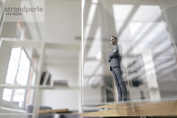 Geschäftsmann-Figur im modernen Büro stehend  Blick durch Glasscheibe