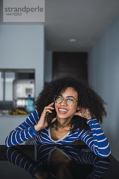 Porträt einer lächelnden jungen Frau am Telefon zu Hause
