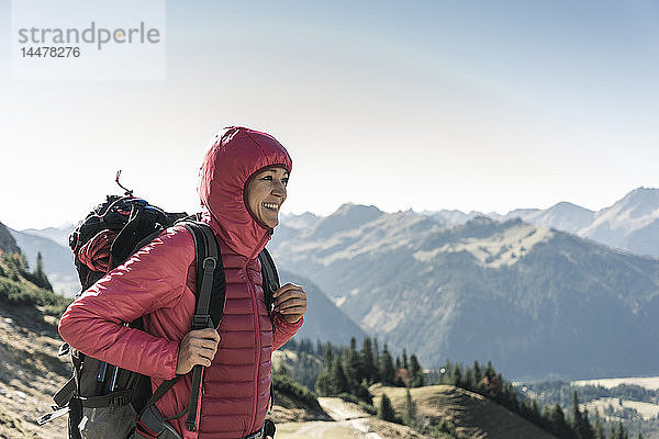 Österreich  Tirol  lächelnde Frau auf einer Wanderung in den Bergen  die die Aussicht genießt