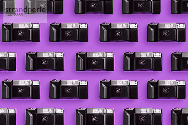 Plastik-Fotokameras in einer Reihe über rosa Hintergrund