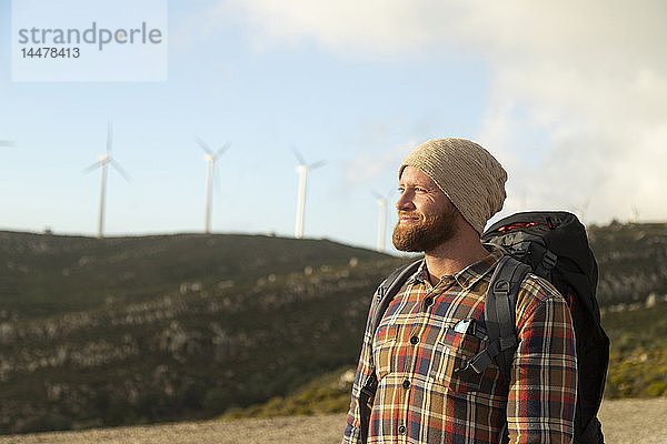 Spanien  Andalusien  Tarifa  lächelnder Mann auf einer Wanderung mit Windturbinen im Hintergrund