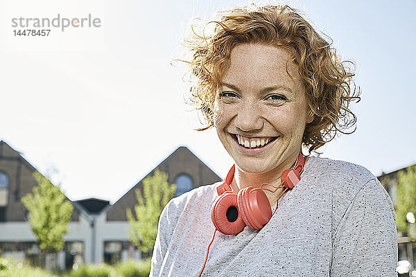 Porträt einer glücklichen jungen Frau mit Kopfhörern in städtischer Umgebung