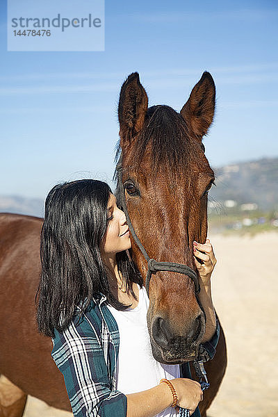 Spanien  Tarifa  Frau kuschelt mit Pferd am Strand