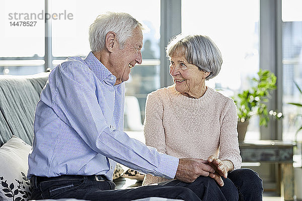 Älteres Ehepaar sitzt auf der Couch und unterhält sich miteinander