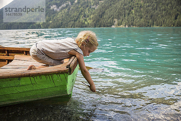 Österreich  Kärnten  Weissensee  Mädchen im Ruderboot  das einen Stock ins Wasser wirft