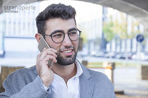 Porträt eines lächelnden jungen Geschäftsmannes am Telefon