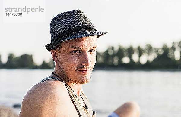 Porträt eines jungen Mannes mit Hut am Flussufer