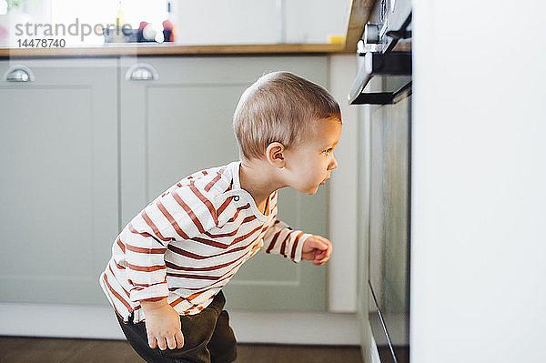Kleinkind schaut zu Hause in der Küche auf den Ofen