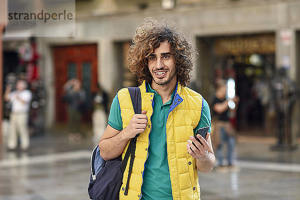 Spanien  Granada  Porträt eines lächelnden jungen Touristen mit Rucksack  der die Stadt entdeckt