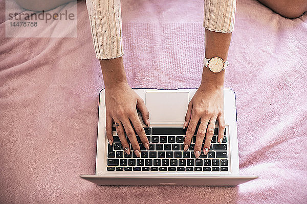 Frauenhand mit Laptop auf dem Bett  Draufsicht