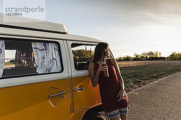 Hübsche Frau auf einer Autoreise mit ihrem Wohnmobil  die bei Sonnenuntergang eine Pause macht