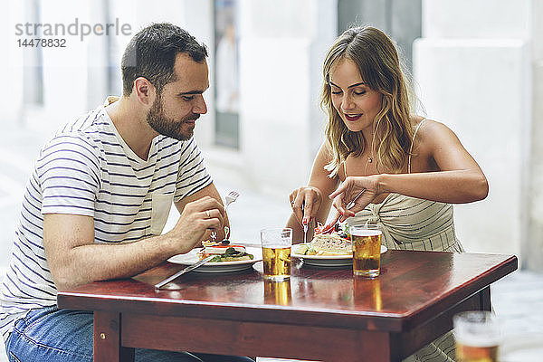 Ein Paar isst und trinkt Bier in einem Restaurant auf der Straße