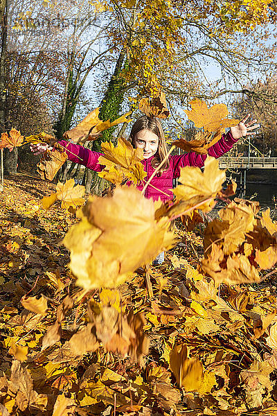 Mädchen wirft Herbstblätter in die Luft