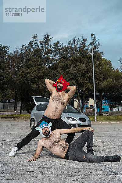 Schwules Paar mit Tierhüten auf dem Parkplatz posierend