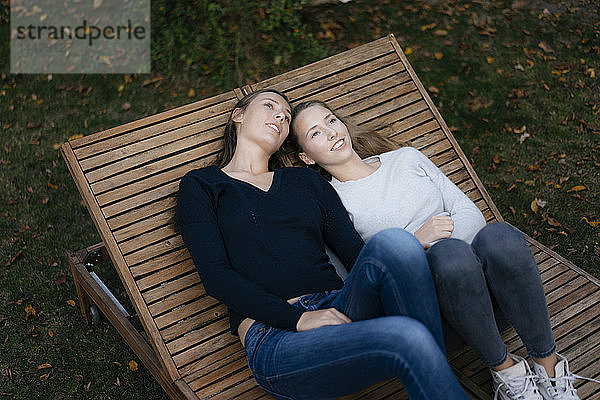Zwei liebevolle  nachdenkliche Teenager-Mädchen ruhen sich auf einer Sonnenliege aus