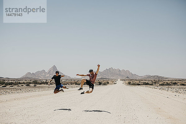 Namibia  zwei Freunde springen auf die Straße nach Spitzkoppe