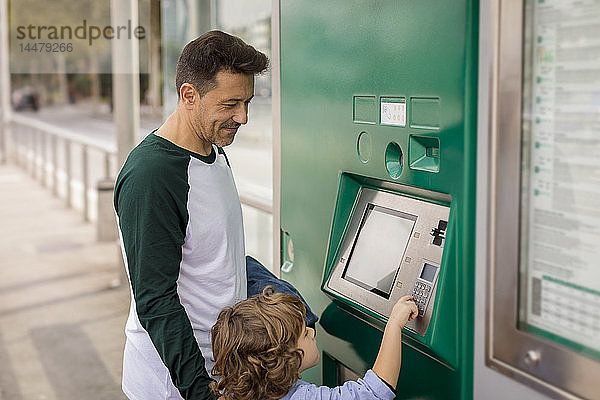 Vater und Sohn benutzen den Fahrkartenautomaten an der Straßenbahnhaltestelle in der Stadt