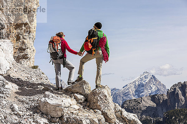 Italien  Cortina d'Ampezzo  Paar mit Seil und Kletterausrüstung hält sich an den Händen und schaut auf die Aussicht