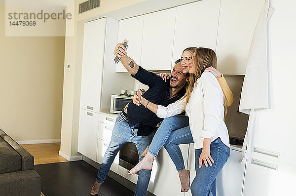 Freunde haben Spaß daran  in der Küche zu stehen und mit ihren Smartphones Fotos zu machen
