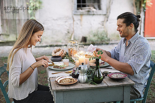 Paar beim romantischen Essen bei Kerzenlicht neben einer Hütte
