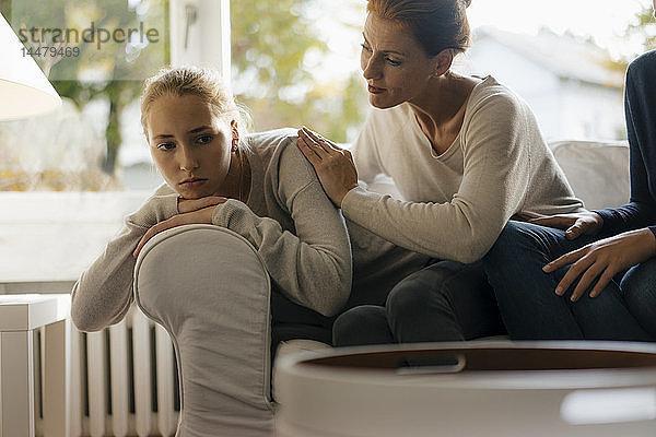 Mutter tröstet trauriges Teenager-Mädchen zu Hause auf der Couch