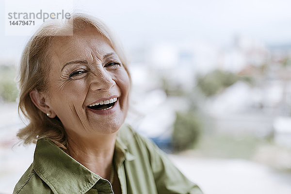 Porträt einer lachenden älteren Frau mit Hörgerät im Freien