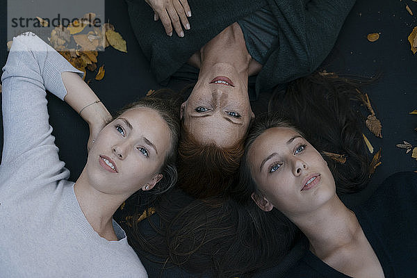 Mutter mit zwei Mädchen im Teenageralter im Herbst auf dem Trampolin liegen