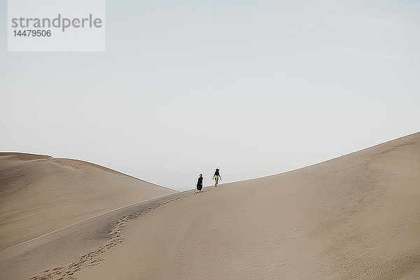 Namibia  Namibia  Namib  Rückenansicht von zwei Frauen auf einer Wüstendüne